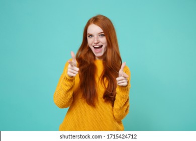 Excited Young Redhead Woman Girl In Yellow Sweater Posing Isolated On Blue Turquoise Wall Background Studio Portrait. People Lifestyle Concept. Mock Up Copy Space. Pointing Index Fingers On Camera