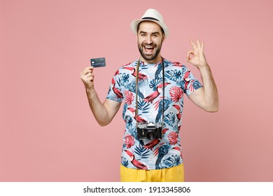 Excited Young Traveler Tourist Man In Summer Clothes Hat Hold Credit Bank Card Showing OK Gesture Isolated On Pink Background Studio. Passenger Traveling Abroad On Weekend. Air Flight Journey Concept