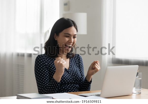 Excited young vietnamese woman look at laptop pc\
screen in delight receiving good news being accepted admitted to\
college university. Overjoyed asian lady office worker get reward\
promotion by email