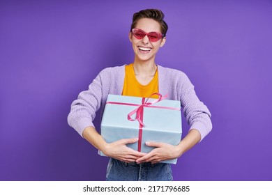 Excited Young Woman Carrying Gift Box While Standing Against Purple Background