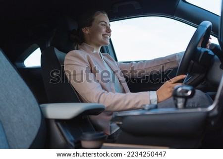 Excited young woman driving her electric car.