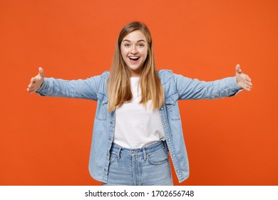Excited young woman girl in casual denim clothes posing isolated on orange background in studio. People lifestyle concept. Mock up copy space. Gesturing demonstrating size with horizontal workspace