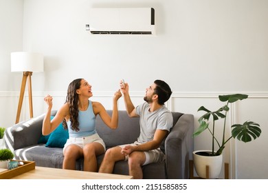 Excited Young Woman And Man Using The Remote To Turn On The Ac Unit To Cool Down During The Hot Weather 