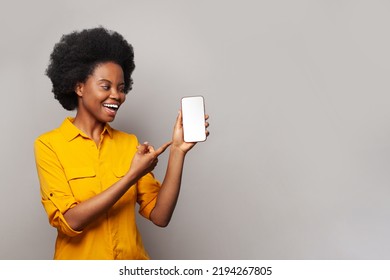 Excited young woman pointing at empty blank screen display smart phone on white background with copy space - Shutterstock ID 2194267805