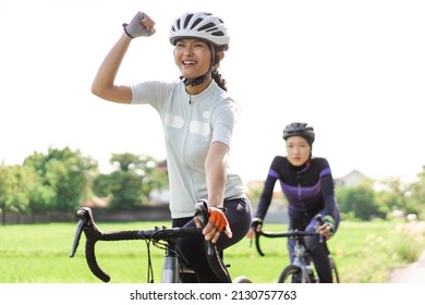 excited young woman riding her road bike with friend - Shutterstock ID 2130757763