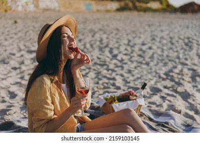 Excited Young Woman In Straw Hat Shirt Summer Clothes Sit On Plaid Have Picnic Drink Red Wine Glass Eat Biting Strawberry Outdoor On Sea Sunrise Sand Beach People Vacation Lifestyle Journey Concept.