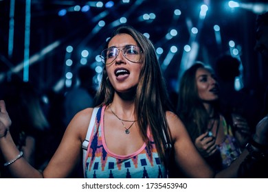 An excited young woman watching her favorite band perform live - Powered by Shutterstock