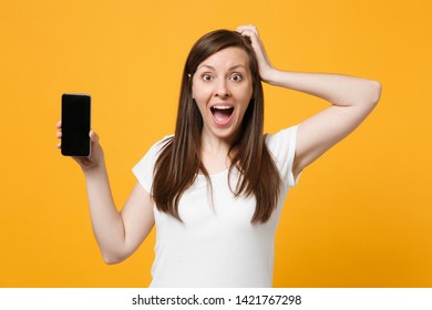 Excited young woman in white casual clothes putting hand on head holding mobile phone with blank empty screen isolated on bright yellow orange background. People lifestyle concept. Mock up copy space - Shutterstock ID 1421767298