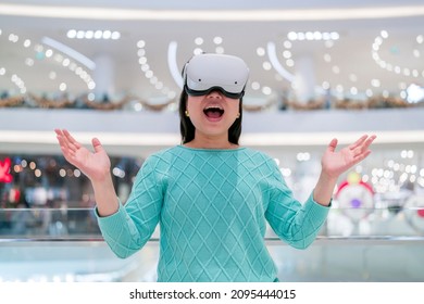 Exciting asian female wearing vr headset getting experience using VR-headset glasses walking through metaverse of virtual department store mall ,asian female enjoying  VR goggles virtual shopping