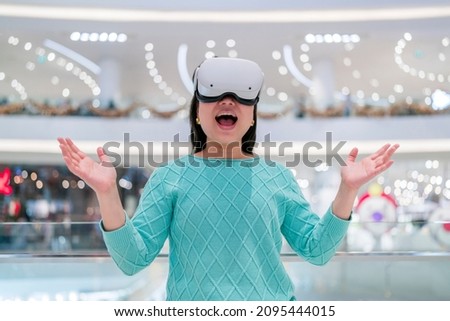 Exciting asian female wearing vr headset getting experience using VR-headset glasses walking through metaverse of virtual department store mall ,asian female enjoying  VR goggles virtual shopping