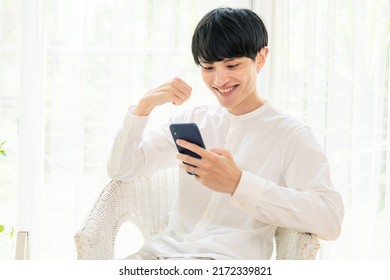 Exciting Asian Man Watching A Smart Phone. Online Sports Broadcast. Social Game.