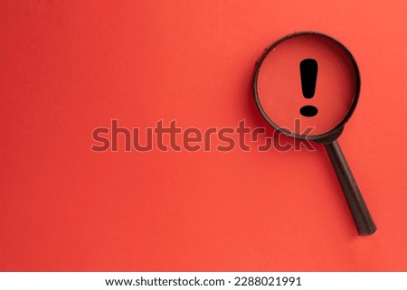 Exclamation mark concept.,Magnifying glass focus on Exclamation mark icon over red background with copyspace for put your text or logo.