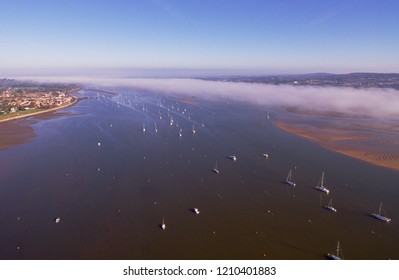 Exe estuary from above by drone. Showing the river exe and lots of boats moored up, on a sunny morning with low cloud in Devon , UK 