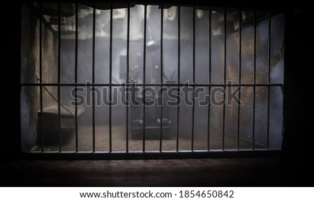 Execution concept. Death penalty electric chair miniature in selective focus inside old prison. Old prison bars cell lock. Creative artwork decoration. Electric chair scale model in the dark