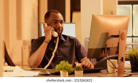 Executive Assistant Answering Landline Phone Call In Office With Big Windows, Having Remote Conversation On Telephone With Cord. Chatting On Phone Line With Coworkers, Communication.