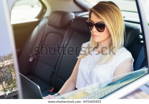 Executive\
businesswoman in car work on her\
laptop.