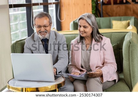Executive discussing with senior professional while working on laptop at office