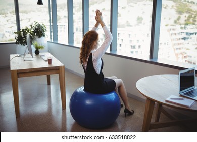 Executive Exercising On Fitness Ball In Office