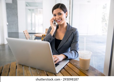 Executive Finance Real Estate Agent At A Coffee Shop Working On A Laptop And Talking On The Cell Phone