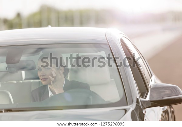 Executive\
looking at rear-view mirror of car on\
road