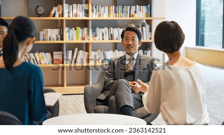 Executive man being interviewed by reporters in lobby.