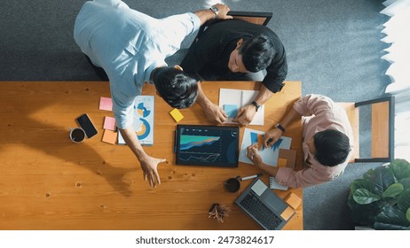 Executive manager explain financial graph to colleague at meeting room. Top aerial view of diverse marketing team sharing idea and planning strategy while sitting at table with tablet. Convocation. - Powered by Shutterstock