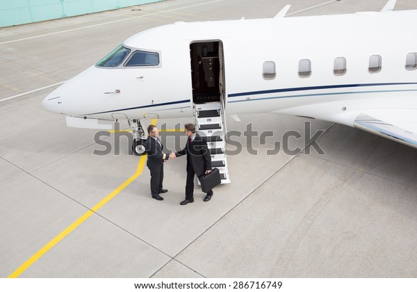 executive manager leaving corporate jet handshake\
with pilot