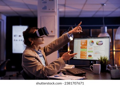Executive manager using hologram to plan financial investment strategy to increase company profit. Businesswoman wearing virtual reality headset, working overtime in startup office