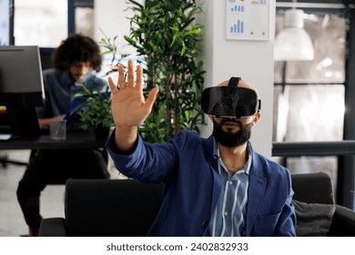 Executive manager using vr glasses for strategy testing in metaverse while working in coworking space. Entrepreneur exploring virtual reality and brainstorming in business office - Powered by Shutterstock