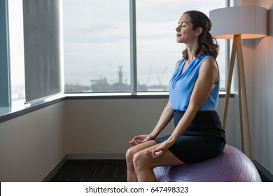 Executive Meditating On Fitness Ball In Office