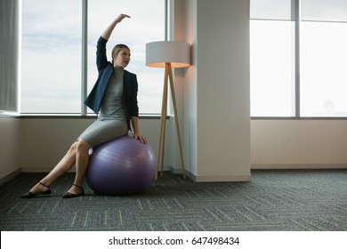 Executive performing stretching exercise on fitness ball in office - Powered by Shutterstock