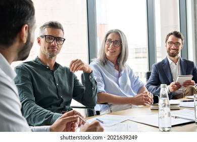 Executive team business people listening to ceo negotiating discussing project at board meeting. Multicultural professional company leaders working together sitting at boardroom table in office. - Shutterstock ID 2021639249