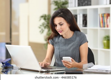 Executive Working On Line With A Laptop And Phone In A Desktop At Office