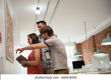 Executives Discussing Over Bulletin Board In Office