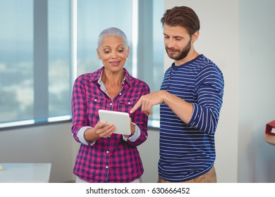  Executives discussing over digital tablet in office