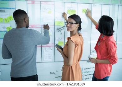 Executives Preparing Sticky Notes On Whiteboard In Office