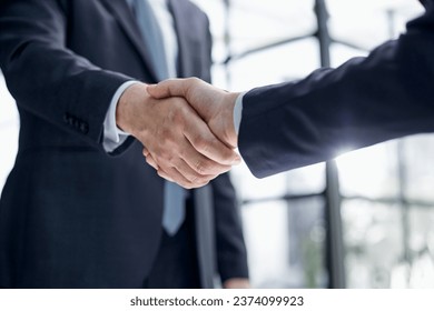 executives shaking hands in front of their manager and a colleague - Powered by Shutterstock