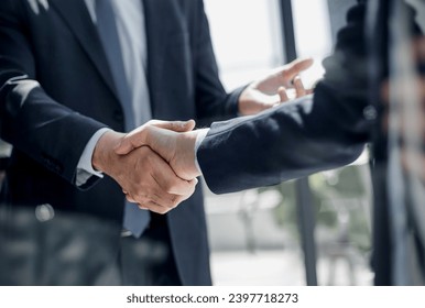 executives shaking hands in front of their manager and a colleague