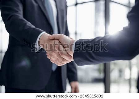 executives shaking hands in front of their manager and a colleague