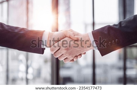 executives shaking hands in front of their manager and a colleague