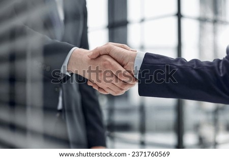 executives shaking hands in front of their manager and a colleague