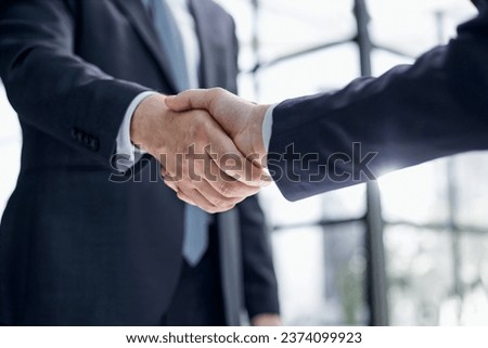 executives shaking hands in front of their manager and a colleague
