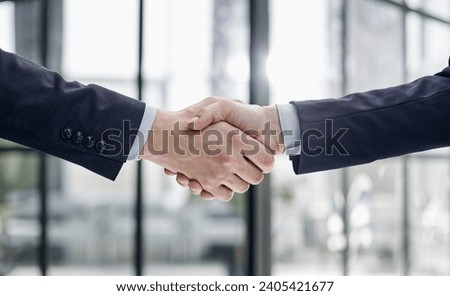 executives shaking hands in front of their manager and a colleague