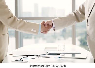 Executives Shaking Hands Over The Table With Business Documents