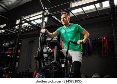 Exercise bicycle, spinning class. Focus on black indoor bikes and a male person working out in the gym. The spinning room inside of modern gym space. Sport, fitness, stay in good psychical shape - Powered by Shutterstock