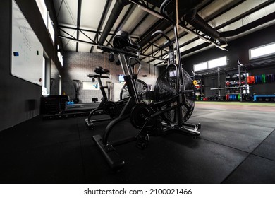 Exercise Bike Indoor Gym. Focus On Black Indoor Bikes In An Empty Gym With No People. Spinning Room Inside Of Modern Gym Space. Sport, Fitness, Stay In Good Psychical Shape, No People