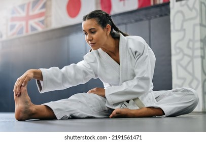 Exercise, fight and workout stretch of a karate school student with focus before training start. Sport woman or coach stretching for an exercise at a dojo studio, performance gym or martial arts - Powered by Shutterstock