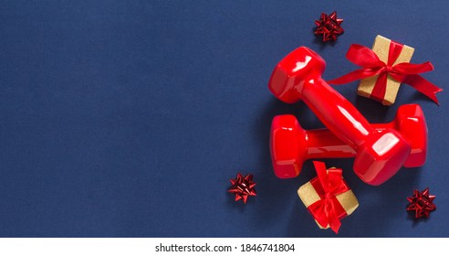 Exercise, fitness and development of the concept of a happy Christmas and a happy New year. Red dumbbells, bows and gifts with red ribbons on a dark blue background.