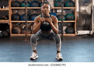 Exercise, fitness and kettlebell with woman squat, workout and gym challenge with weight. African female person, strength training and wellness with sport for muscle and athlete in a health center - Powered by Shutterstock