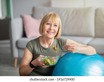 Exercise And Healthy Diet Concept. Senior Woman With Fitball Eating Fresh Vegetable Salad At Home. Mature Caucasian Lady Having Veggies After Sports Training, Keeping Weight Loss Diet